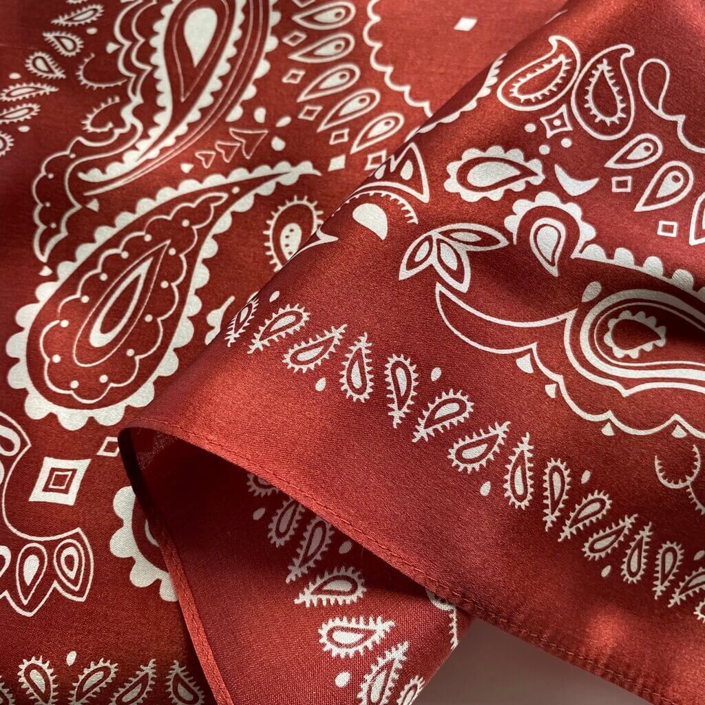 close up of a red mulberry silk bandana with white paisley patterns