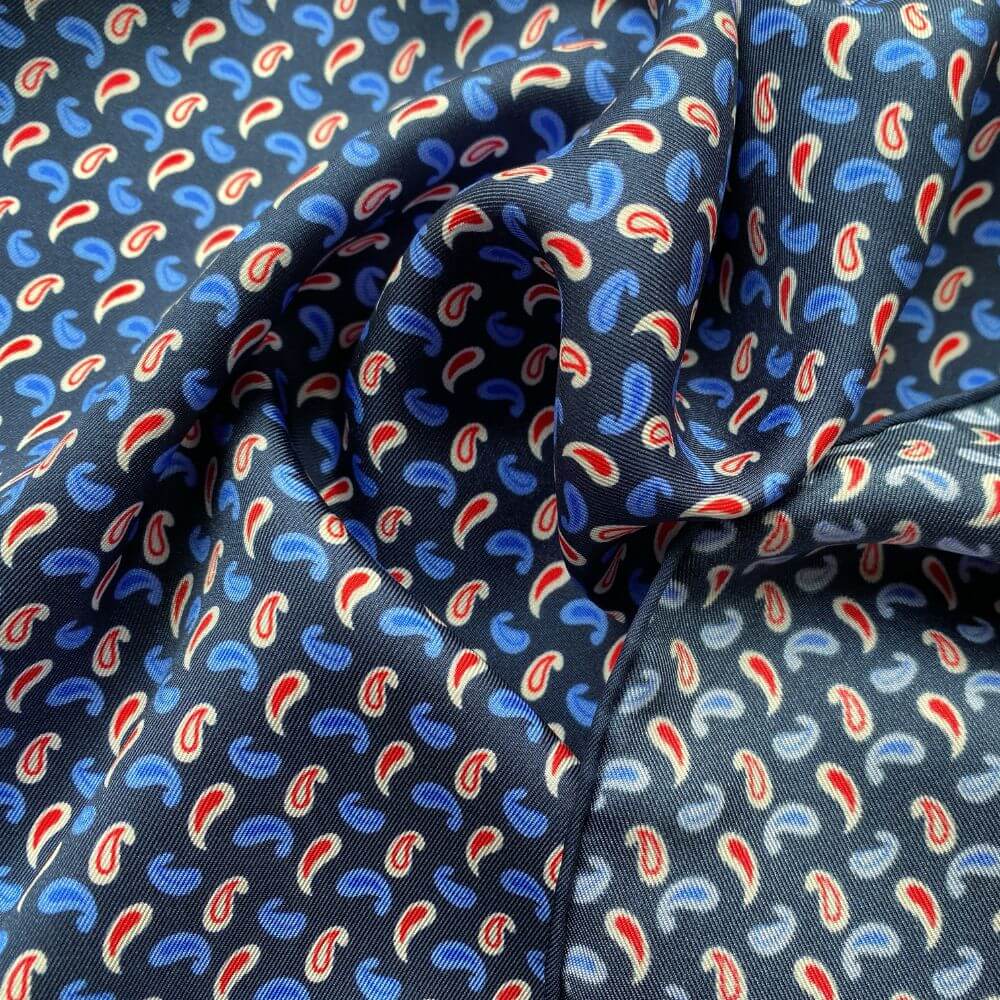 Close-up of a mulberry silk square scarf with blue, red, and white paisley pattern