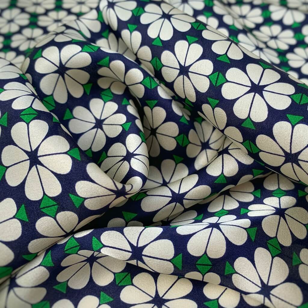 close up of a mulberry silk square bandana scarf with white floral pattern on a blue background