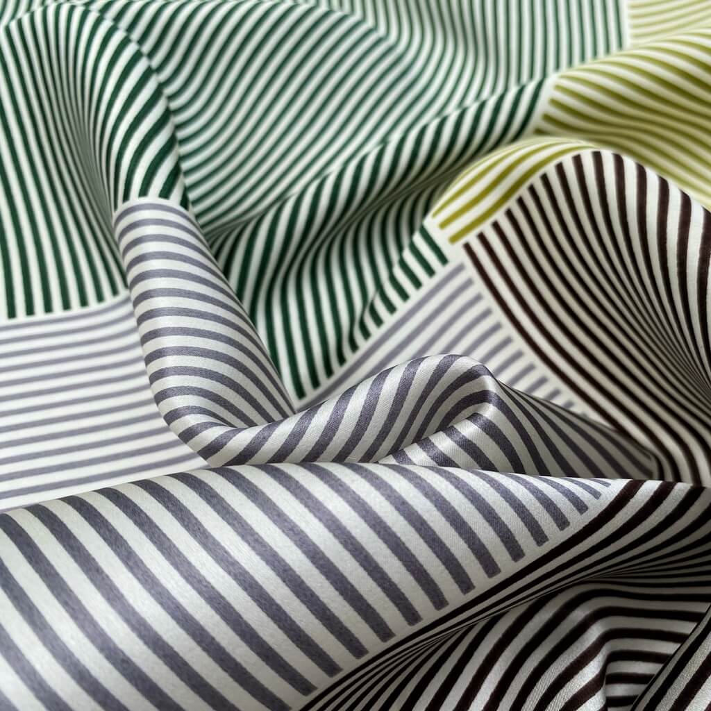 close up mulberry silk square scarf with green, light grey, yellow and white stripes.