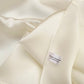 close up of an ivory mulberry silk square scarf with a river minami label