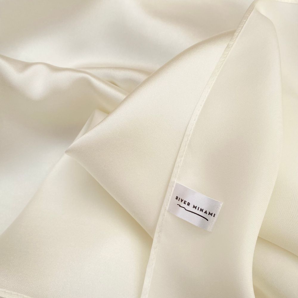 close up of an ivory mulberry silk square scarf with a river minami label