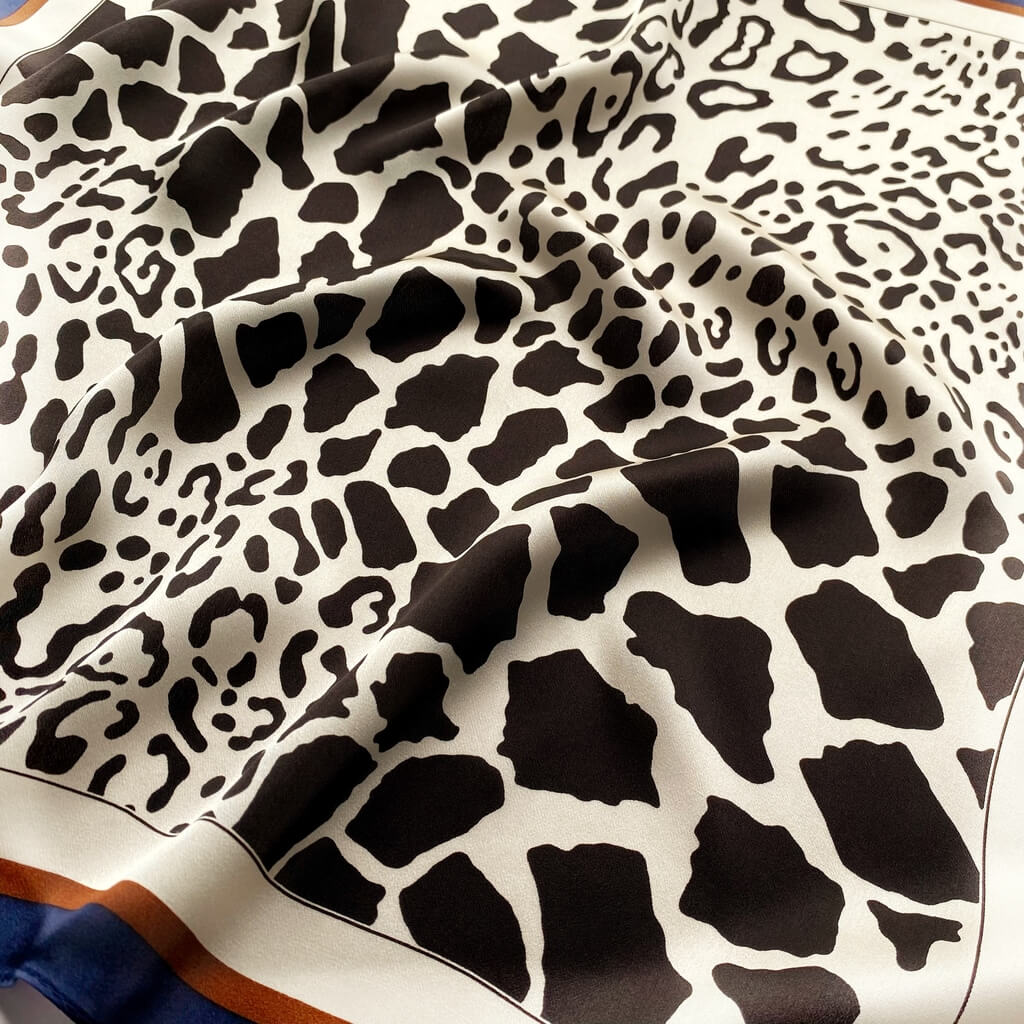 close up a mulberry silk scarf with a black and ivory animal print pattern