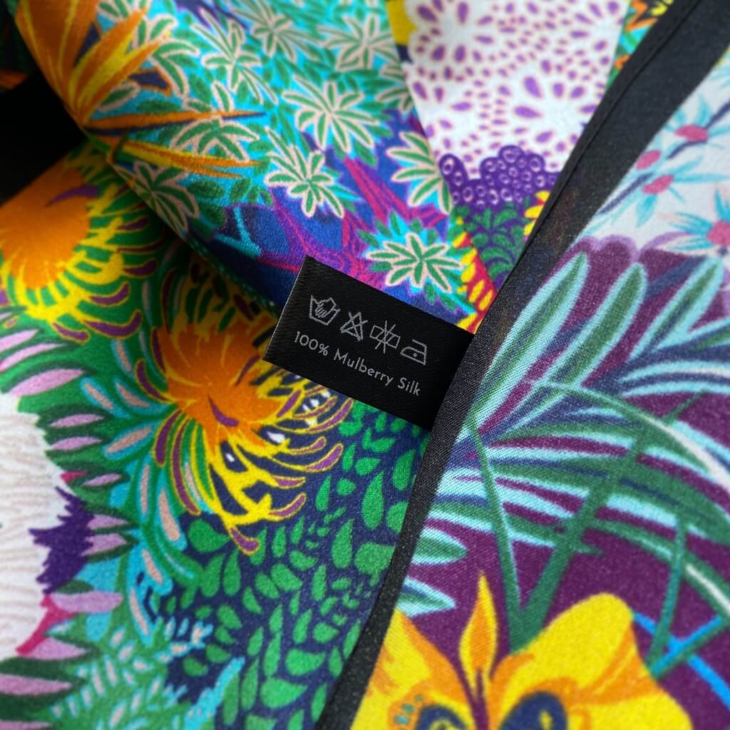 Colorful mulberry silk scarf with a floral pattern and a label indicating 100% mulberry silk.