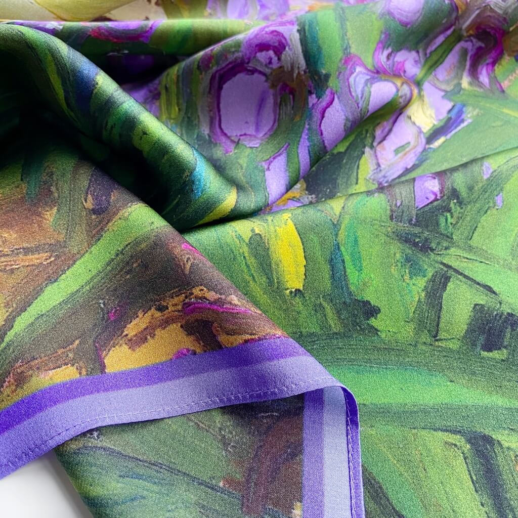 Close-up of colorful mulberry silk satin scarf with green, purple, and yellow patterns.