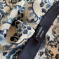 Close-up of the fabric and brand label on a mulberry silk bandana scarf showing the blue-and-white geometric floral print and a tag that reads River Minami 100% silk.