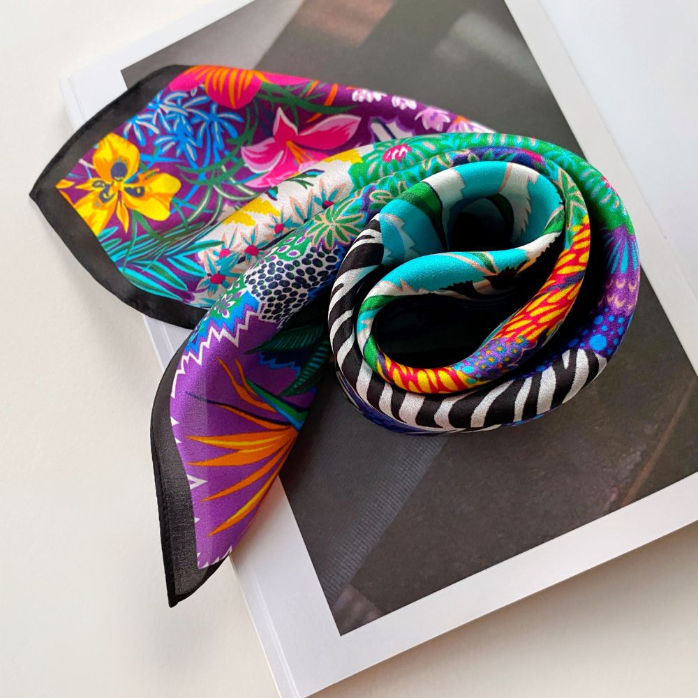 wrapped colourful floral patterned mulberry silk square scarf displayed on a book