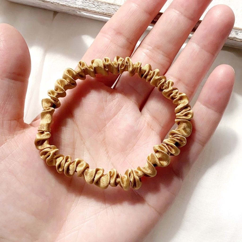hand hold a copper brown mulberry silk satin skinny scrunchie  hair tie