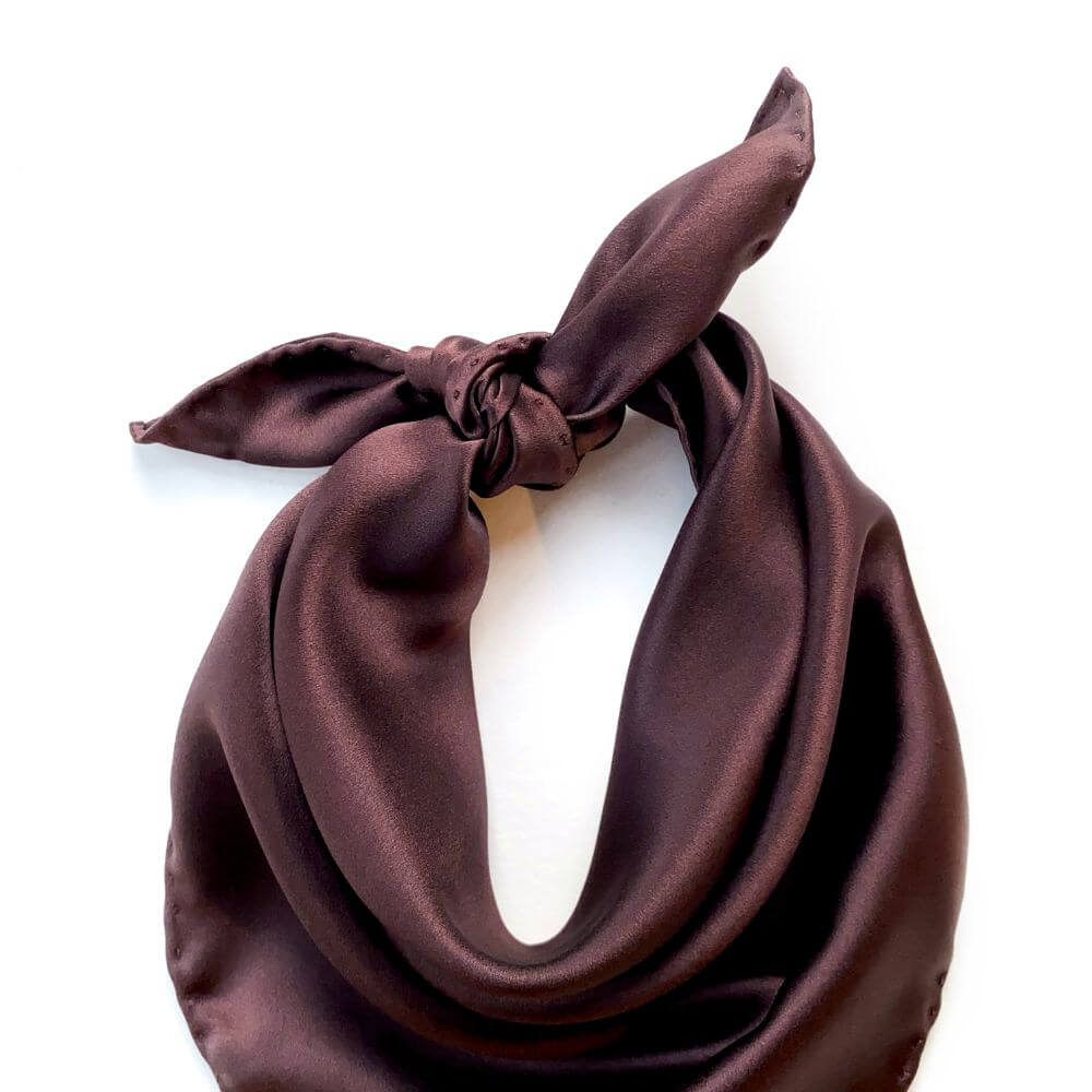 Brown silk scarf tied in a knot on a white background