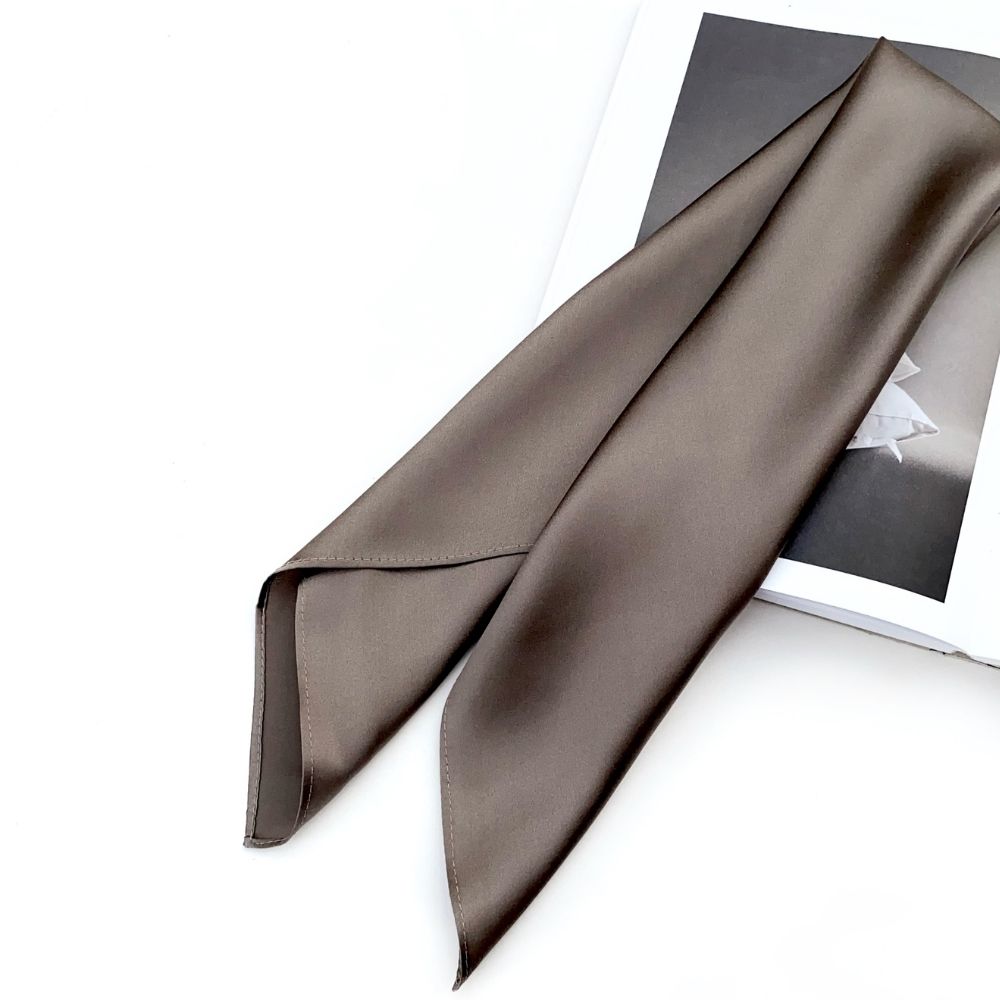 Dark taupe silk satin scarf laid over a book with smooth sheen