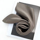 Rolled dark taupe Mulberry silk satin scarf on open magazine page