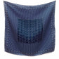 A mulberry silk square scarf in denim blue with a layered geometric, crosshatch, and paisley-inspired design hanging flat on a white wall.