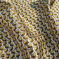close up of a mulberry silk square scarf with a pattern of brown and yellow triangles on a white background