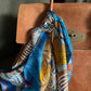Colorful patterned mulberry silk twill square scarf draped over a brown leather handbag.