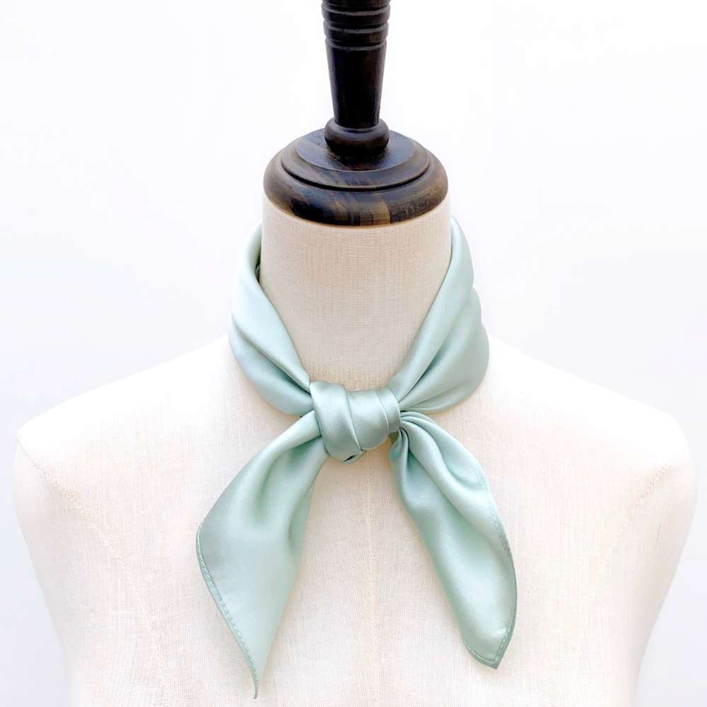 Light blue mulberry silk bandana tied around a mannequin neck on a white background