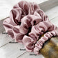 Set of pale mauve silk satin hair scrunchies labeled with size on a wooden surface
