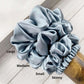 Set of four blue silk hair scrunchies labeled 'Large', 'Medium', 'Small', and 'Skinny' on a wooden surface.