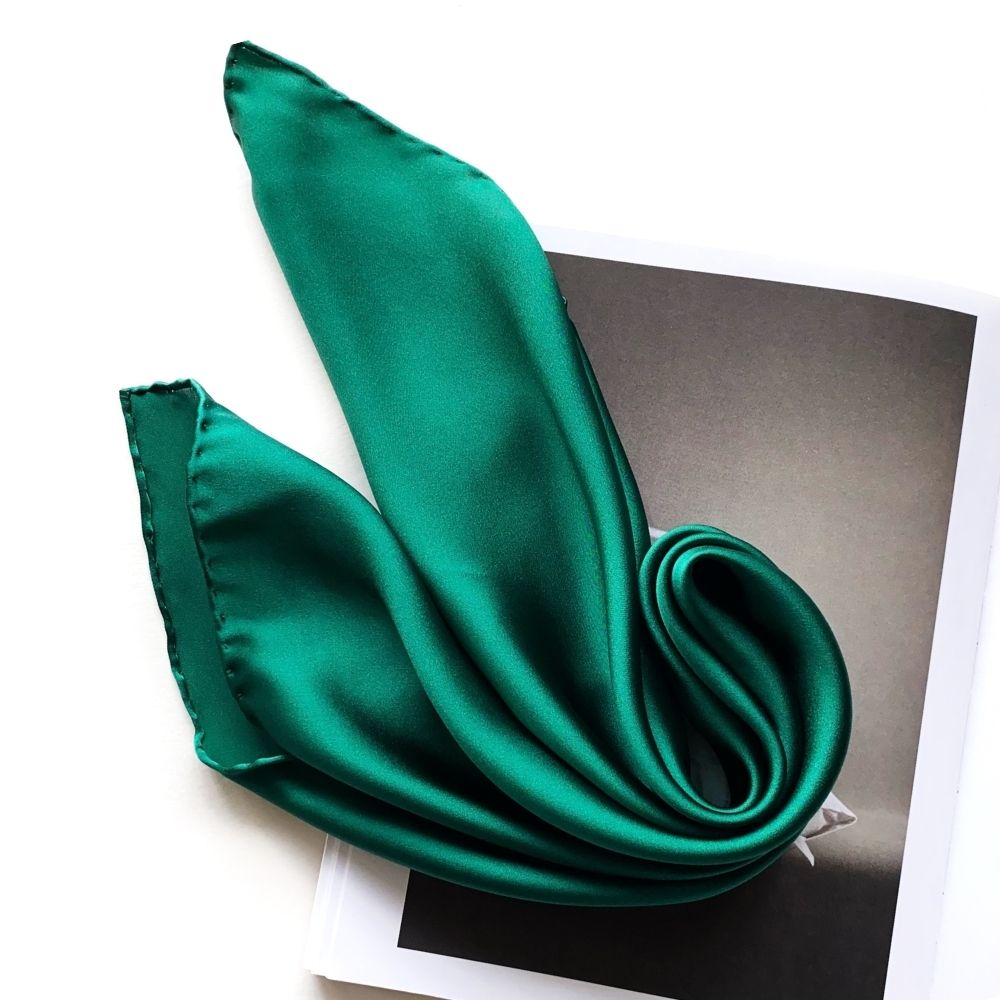 Close-up folded emerald green silk satin scarf on a magazine