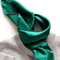 Emerald green silk scarf styled around a grey knit jumper