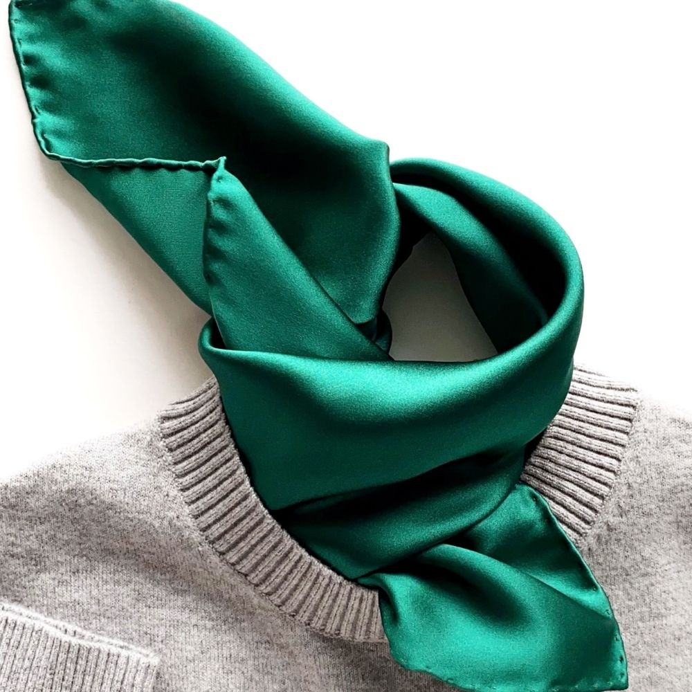 Emerald green silk scarf styled around a grey knit jumper