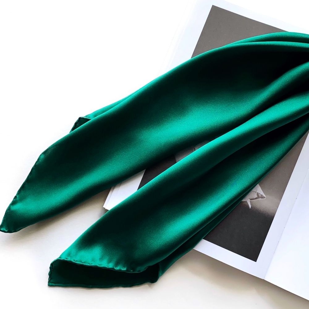 Long view of emerald green silk scarf draped over magazine pages