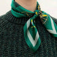 Person wearing an emerald green mulberry silk square scarf with a compass print tied around their neck.
