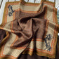 Flat lay of a brown Japanese-print pure mulberry silk square scarf featuring detailed horse designs on a wooden surface.