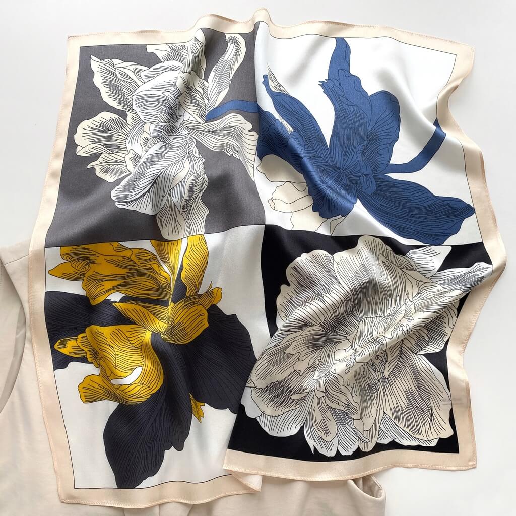 Floral patterned mulberry silk square scarf with blue, yellow, and white flowers with cream border on a white background