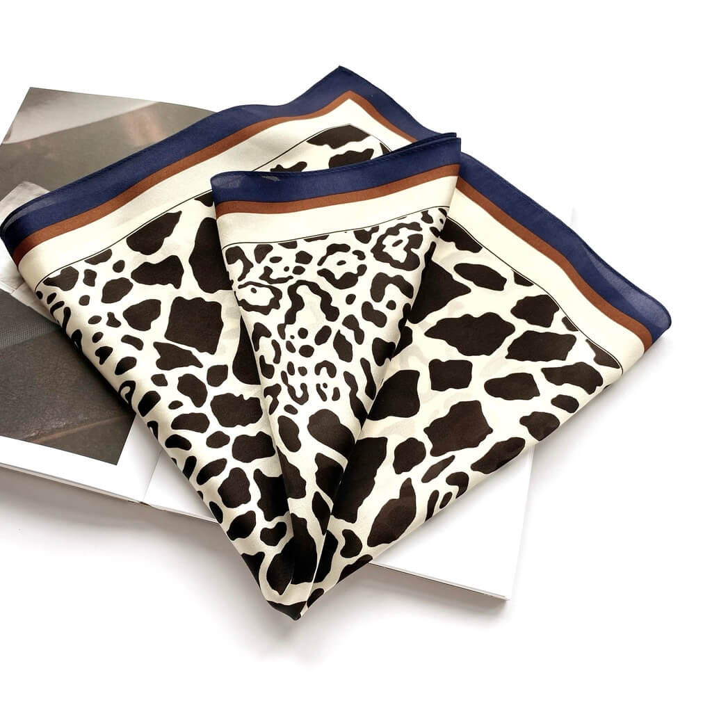 folded black leopard print on ivory background mulberry silk square scarf with blue and brown borders on a white background