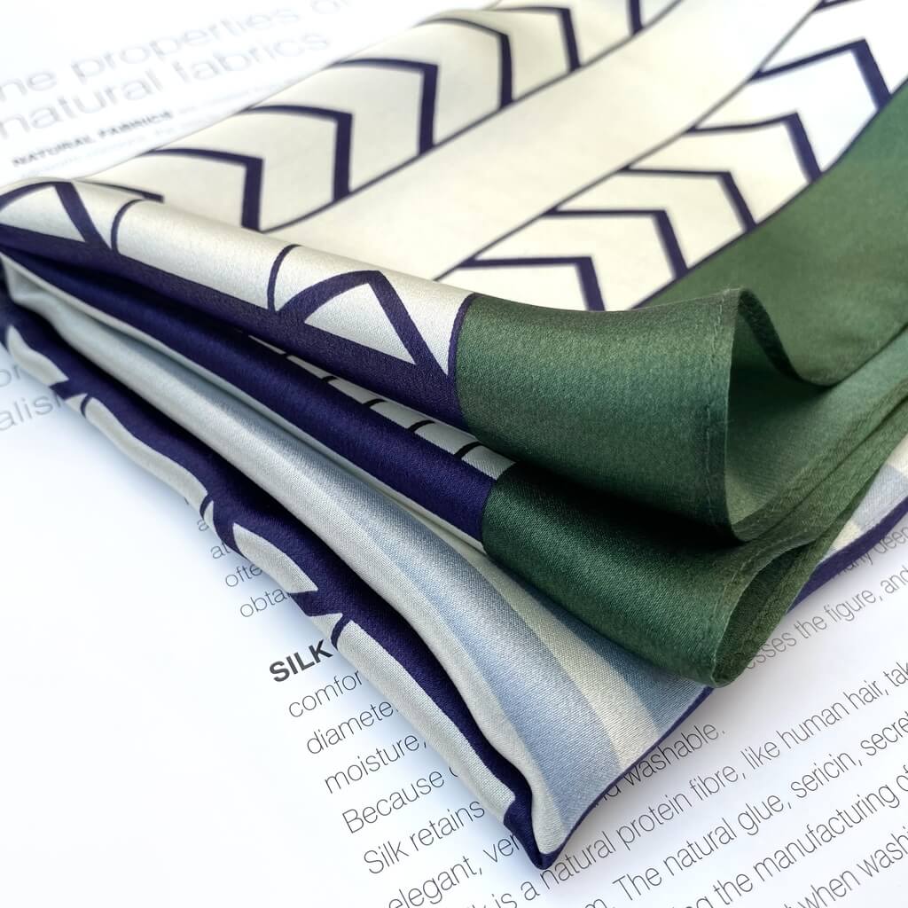folded blue white and green mulberry silk scarf with geometric pattern on a magazine page