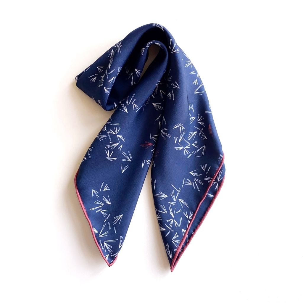 navy blue mulberry silk twill neck scarf folded neatly, featuring white and red geometric accents.