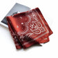 folded brick red mulberry silk square scarf with white paisley pattern on a white background