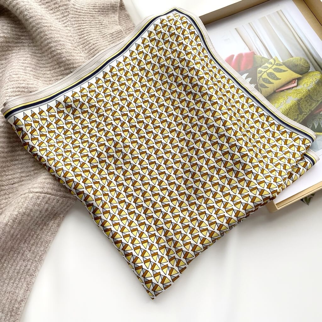 yellow brown mulberry silk square scarf with geometric design on a light surface