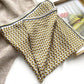 Folded yellow brown mulberry silk square scarf with geometric pattern on a magazine