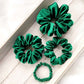 Set of green silk scrunchies on a wooden surface