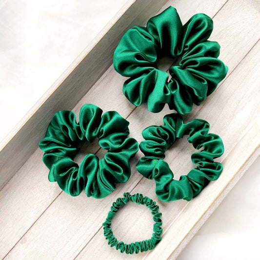 Set of green silk scrunchies on a wooden surface