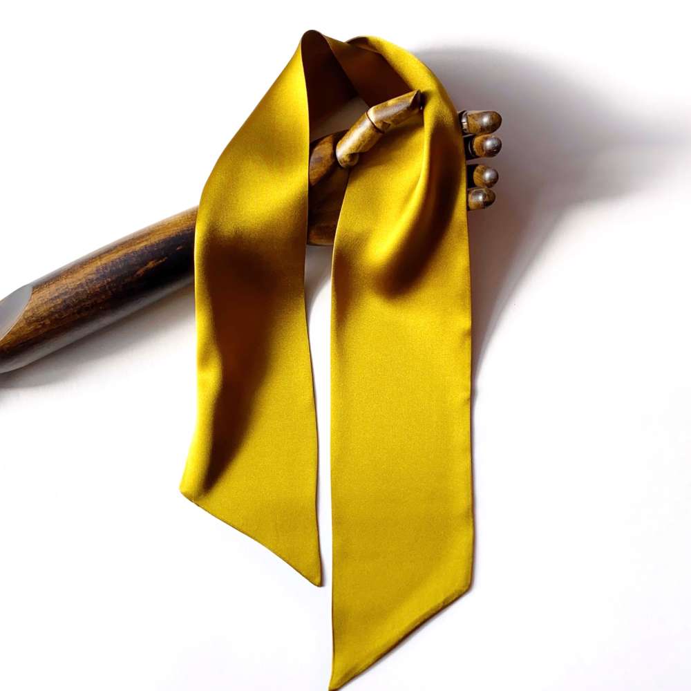 golden olive coloured silk long scarf with wooden hand on a white background
