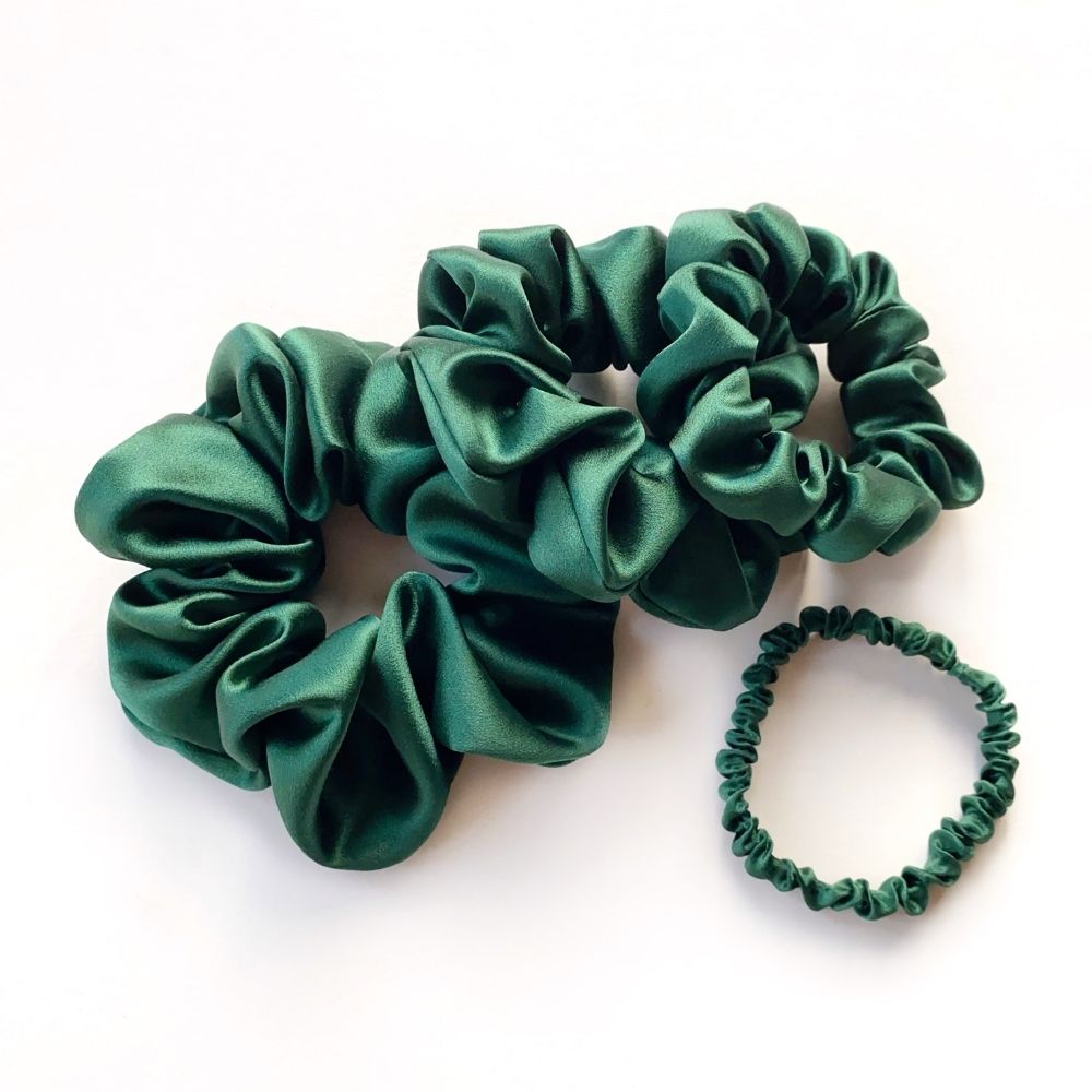 Set of green mulberry silk satin scrunchies and hair ties on a white background