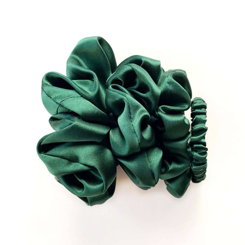 Set of green mulberry silk satin scrunchies and hair ties on a white background