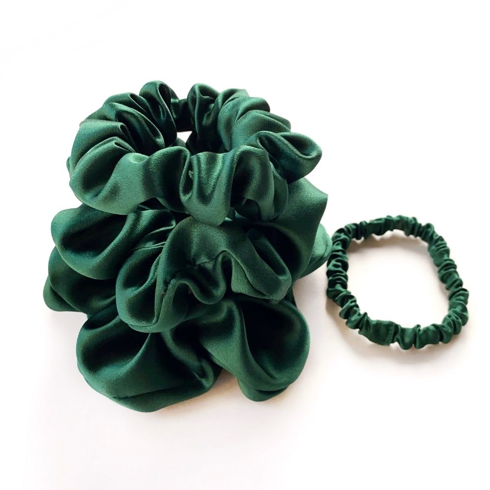 Set of green mulberry silk satin scrunchies and hair ties on a white background