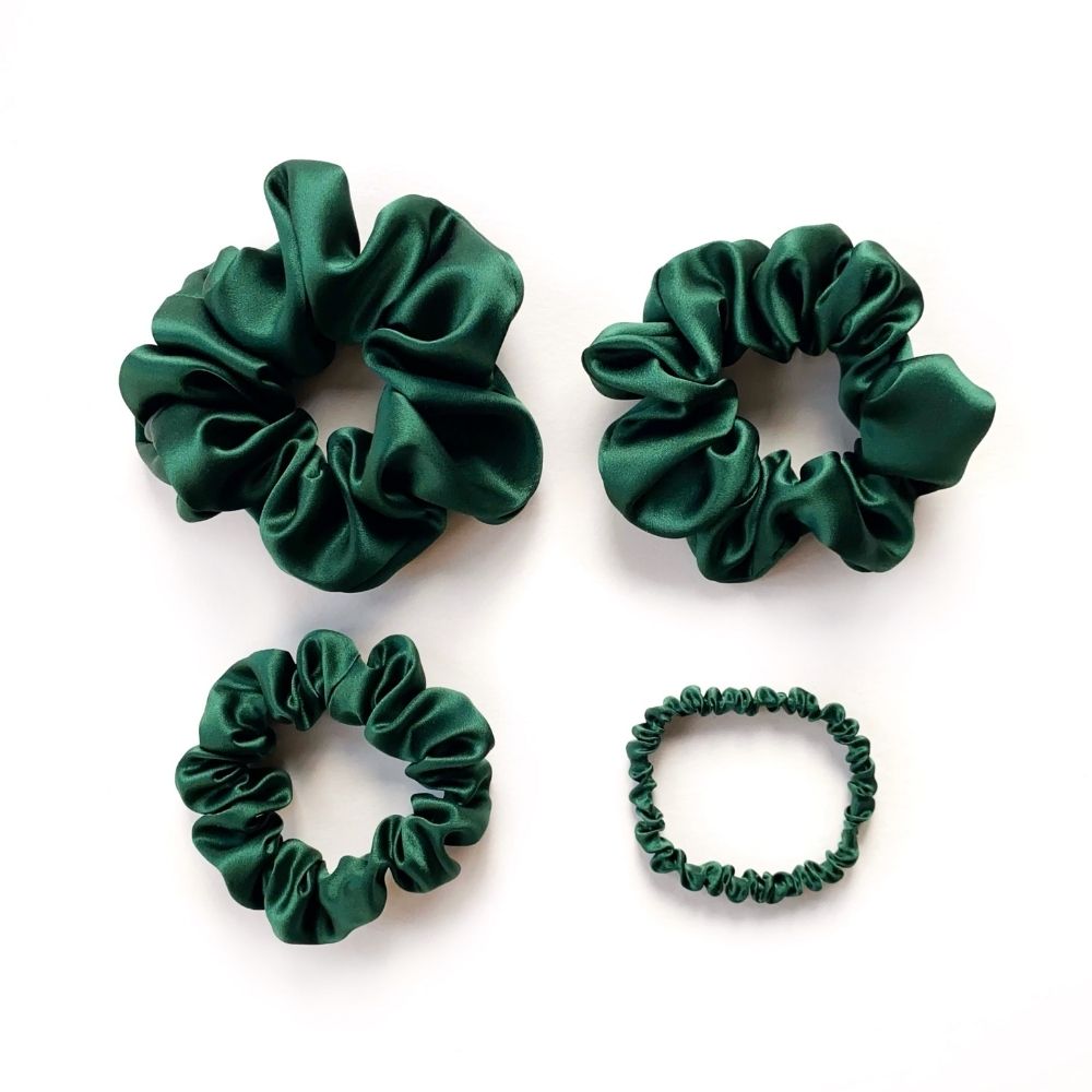 Set of green mulberry silk satin scrunchies and hair ties on a white background