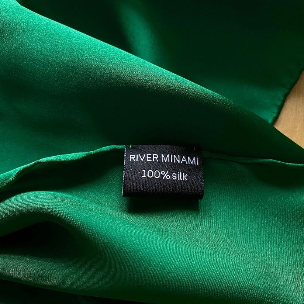 Close-up of Jade Green Mulberry silk satin fabric with River Minami label