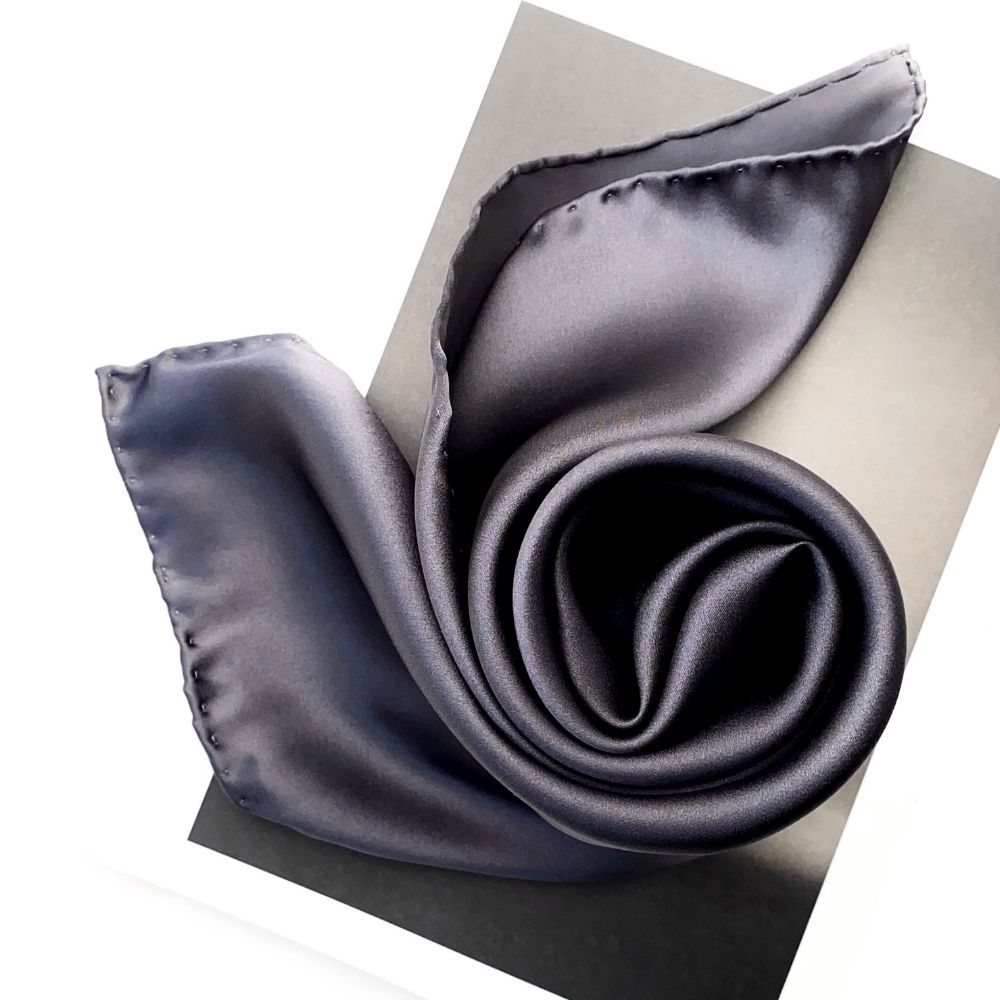 Slate grey silk satin scarf styled in a twisted loop with hand-rolled hem visible.