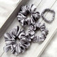 Set of gray mulberry silk satin scrunchies on a light wooden surface