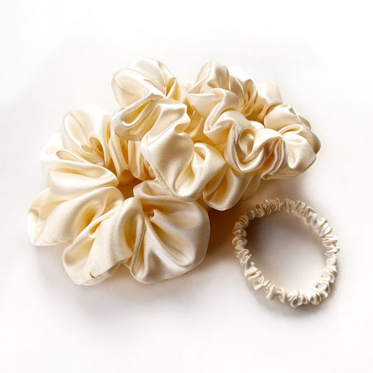 Set of cream-colored mulberry silk satin scrunchies and a hair tie on a white background