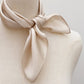 ivory beige silk scarf tied around a mannequin with a plain background