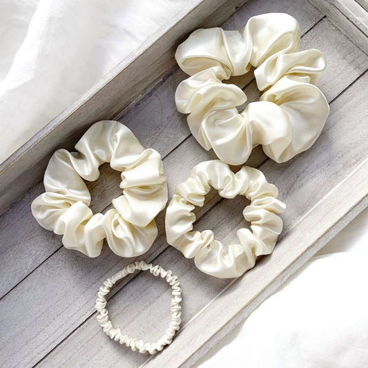 Set of ivory cream mulberry silk satin scrunchies on a wooden surface