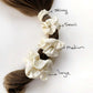Set of four ivory cream mulberry silk satin scrunchies on a ponytail with size labels.