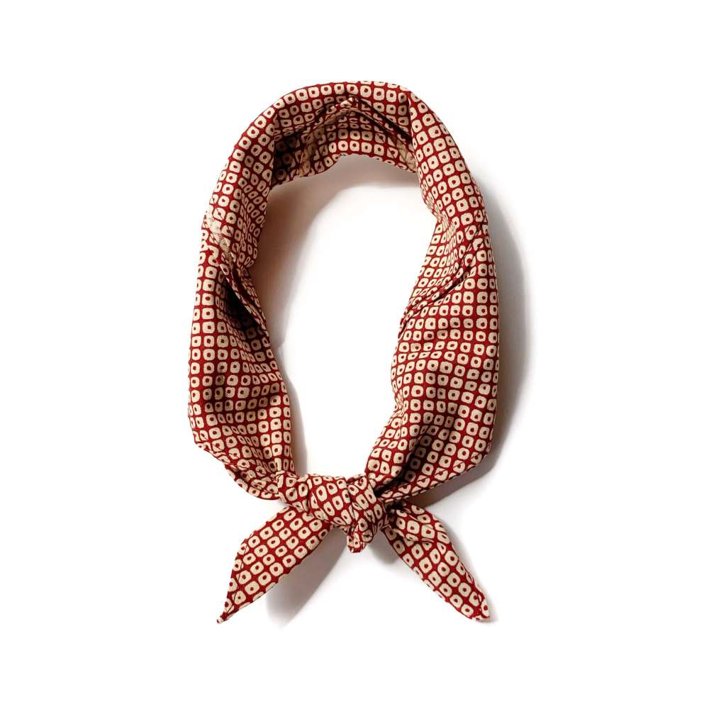 Red Kanoko cotton bandana scarf tied in a loose knot, flat lay on white background