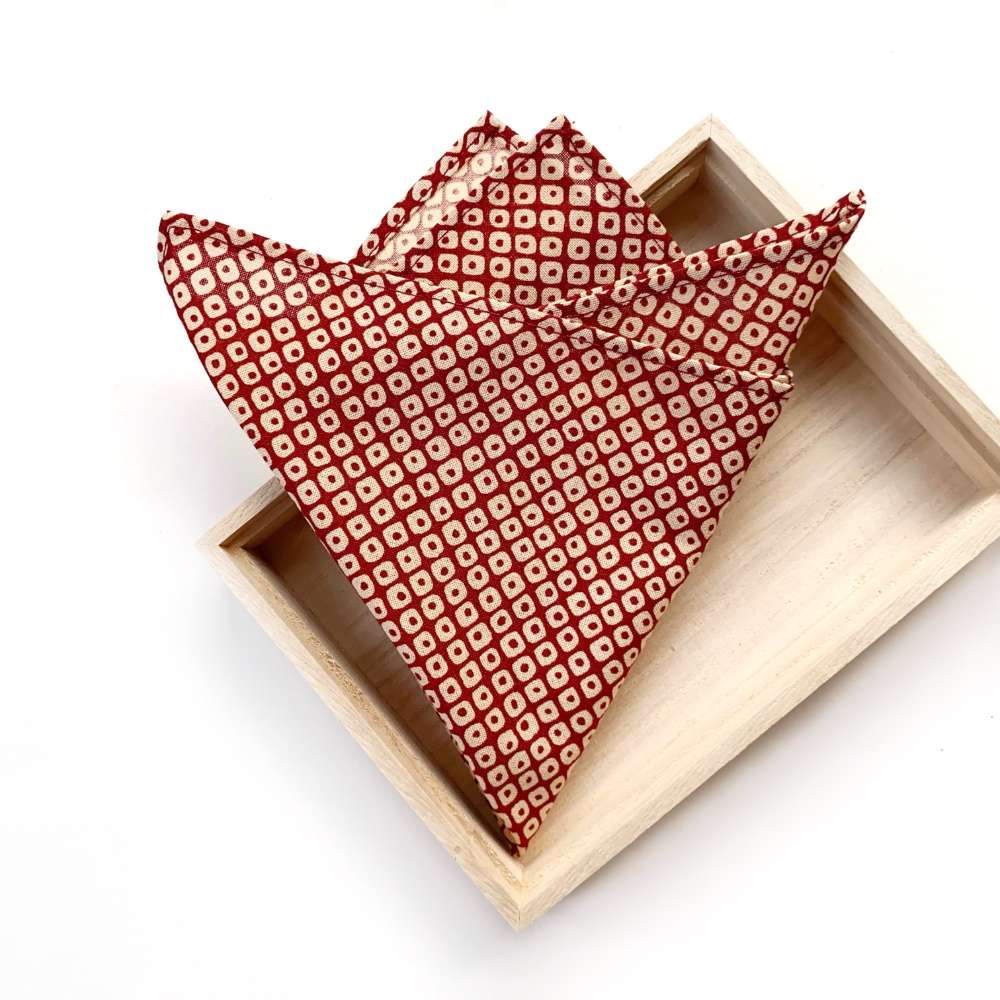 Red japanese cotton packet square folded in half on a wooden tray with a white background